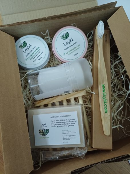 Caja con productos ecológicos de cuidado personal, incluyendo cremas y un cepillo de dientes.